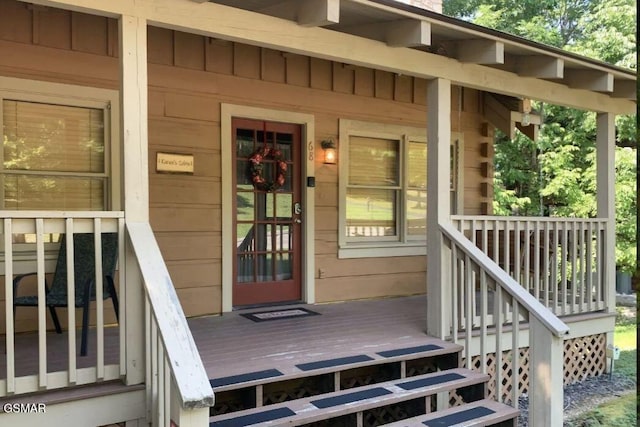 view of exterior entry with covered porch and a deck