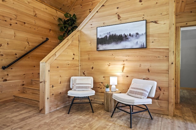 sitting room featuring wood-type flooring, wooden walls, and vaulted ceiling