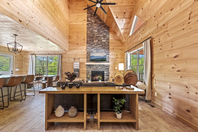 living room featuring light hardwood / wood-style floors, high vaulted ceiling, and wood walls