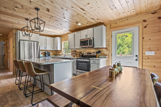 kitchen with a center island, dark hardwood / wood-style flooring, wooden ceiling, and stainless steel appliances