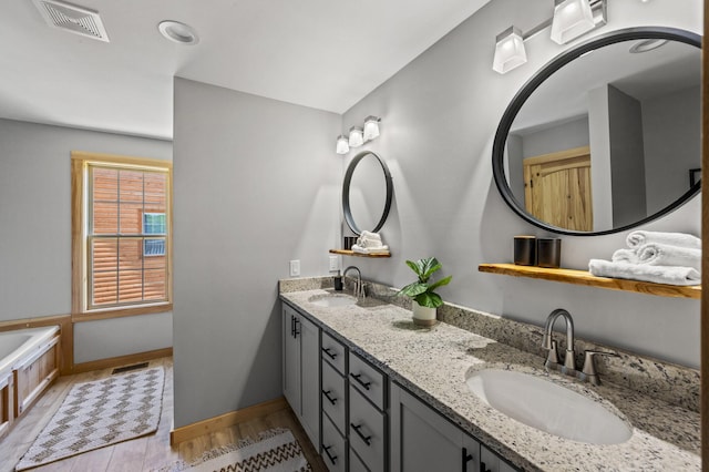 bathroom with a washtub, vanity, and hardwood / wood-style flooring