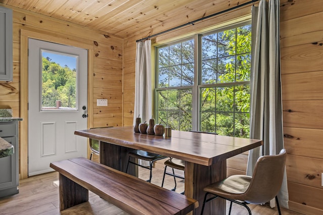 dining room with wood walls, light hardwood / wood-style flooring, and wood ceiling