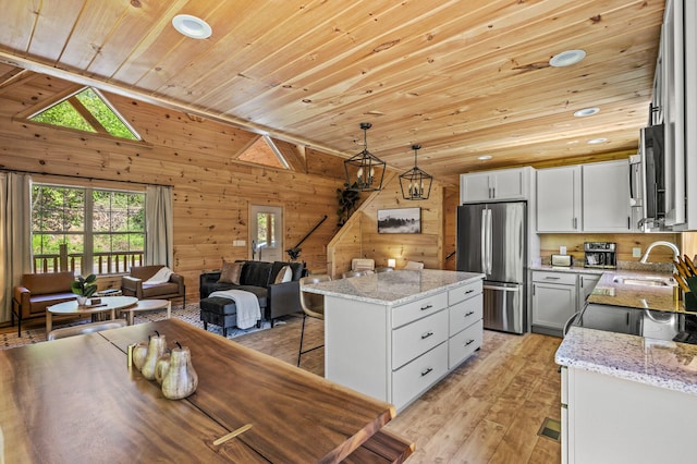 kitchen featuring wood ceiling, wooden walls, pendant lighting, a center island, and stainless steel refrigerator