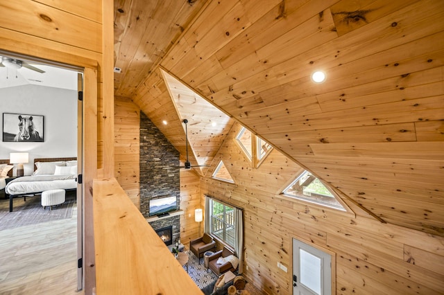 additional living space featuring wood walls, a skylight, ceiling fan, a fireplace, and wood ceiling