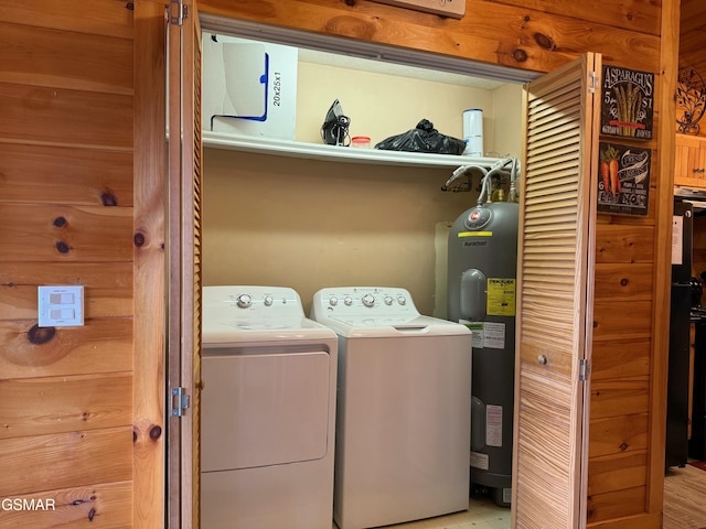 washroom with washing machine and clothes dryer, electric water heater, and wooden walls