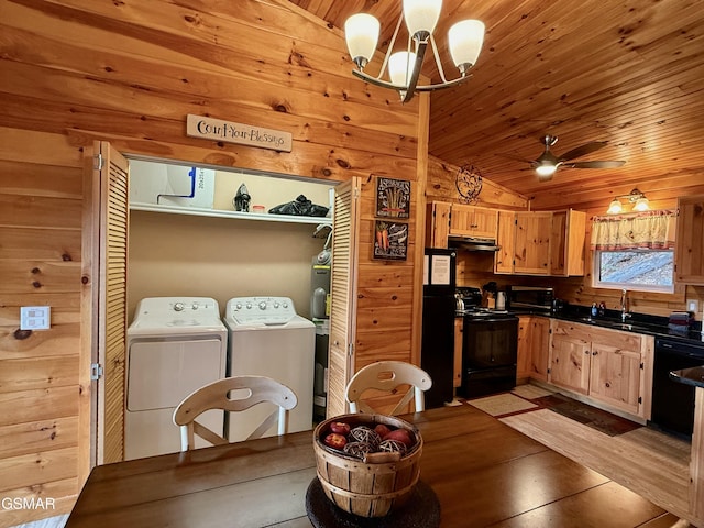 kitchen with washing machine and dryer, wooden walls, black appliances, and vaulted ceiling