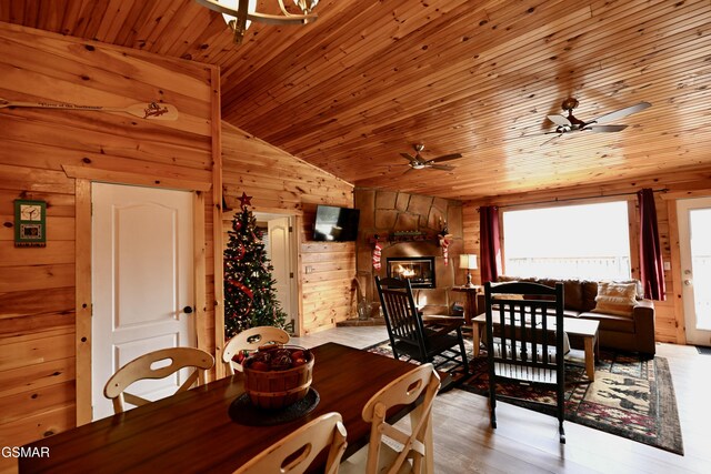 dining space featuring ceiling fan, wooden walls, light hardwood / wood-style flooring, wooden ceiling, and lofted ceiling