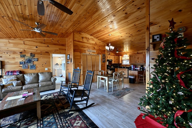 living room with ceiling fan with notable chandelier, vaulted ceiling, hardwood / wood-style flooring, wooden ceiling, and wood walls