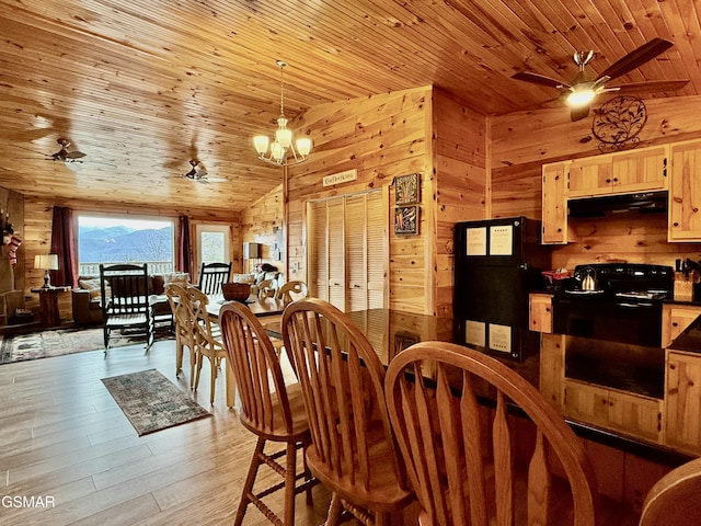 dining area with wood ceiling, an inviting chandelier, light hardwood / wood-style flooring, a mountain view, and wood walls