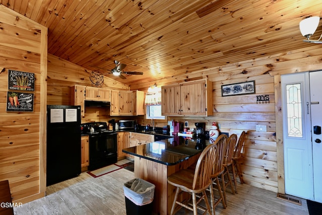 kitchen featuring kitchen peninsula, light hardwood / wood-style flooring, vaulted ceiling, and black appliances