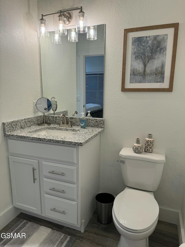 bathroom with toilet, wood finished floors, and vanity
