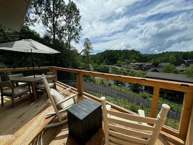 wooden deck with outdoor dining space and a wooded view