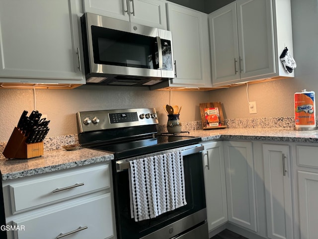 kitchen with stainless steel appliances, light stone countertops, and a textured wall