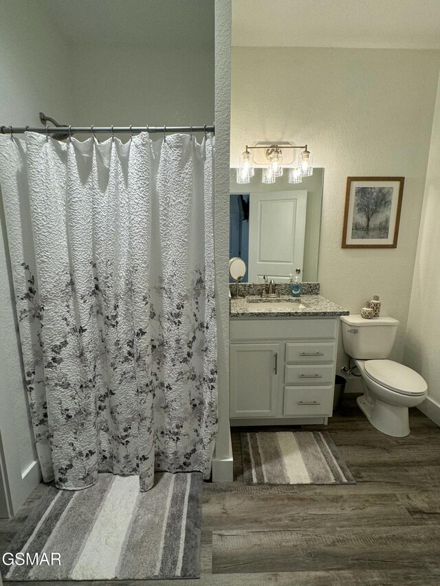 bathroom with baseboards, curtained shower, toilet, vanity, and wood finished floors
