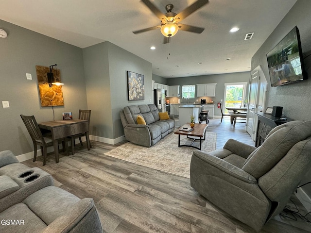 living room featuring visible vents, baseboards, ceiling fan, recessed lighting, and light wood-style flooring
