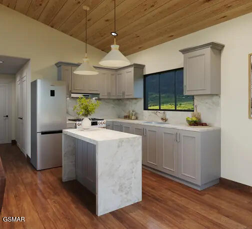 kitchen featuring gray cabinetry, a sink, freestanding refrigerator, exhaust hood, and light countertops