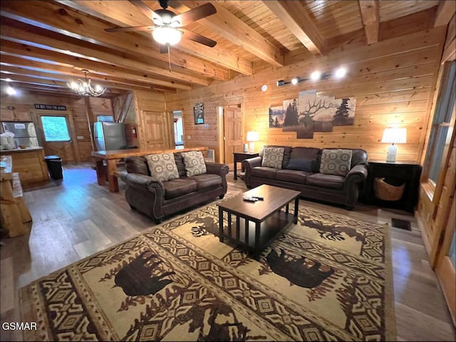 311 Caney Creek Rd, Pigeon Forge, TN 37863 - living room featuring wood walls, light wood finished floors, a ceiling fan, a chandelier, and a wooden ceiling with exposed beams