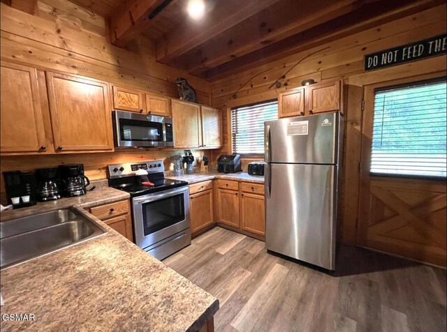 311 Caney Creek Rd, Pigeon Forge, TN 37863 - kitchen featuring appliances with stainless steel finishes, beam ceiling, light wood-style floors, wooden walls, and light countertops