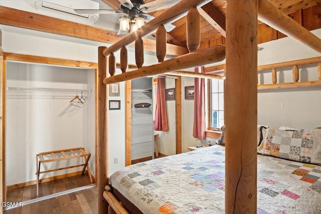 bedroom with beam ceiling and wood finished floors
