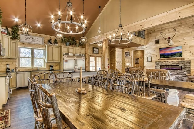 604 Cherokee Orchard Rd, Gatlinburg, TN 37738 - dining space featuring a chandelier, wood walls, dark wood-type flooring, high vaulted ceiling, and a stone fireplace