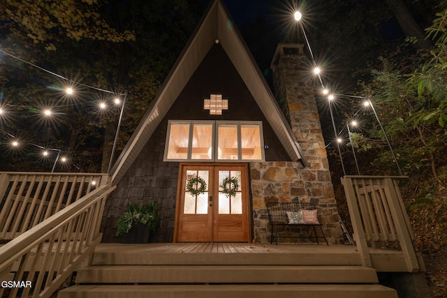 exterior entry at twilight with a deck, french doors, and a chimney