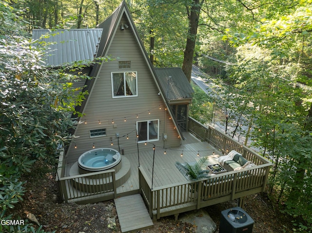 rear view of house featuring an outdoor hot tub, metal roof, a deck, and central AC unit