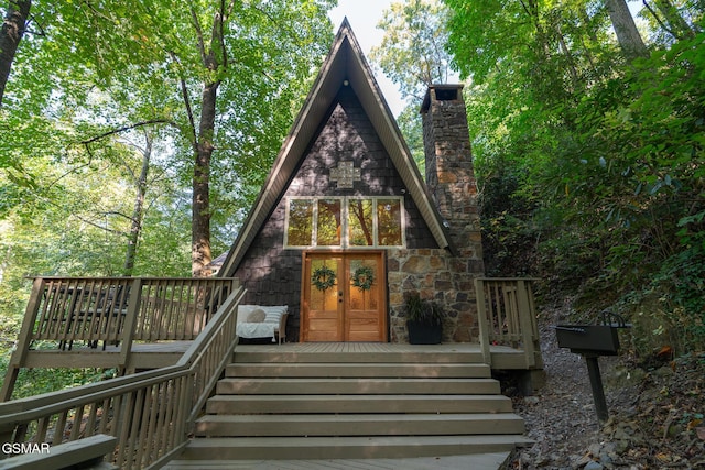 exterior space with a wooden deck, a chimney, and french doors