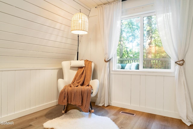 living area with baseboards, plenty of natural light, visible vents, and wood finished floors