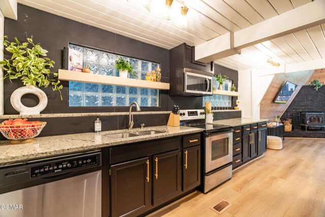 kitchen featuring light stone counters, beam ceiling, appliances with stainless steel finishes, wood ceiling, and a sink