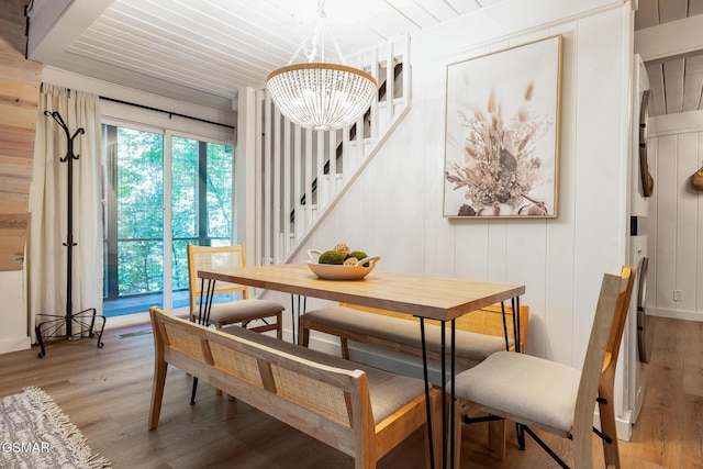 dining area with light wood finished floors, wood ceiling, stairs, and an inviting chandelier