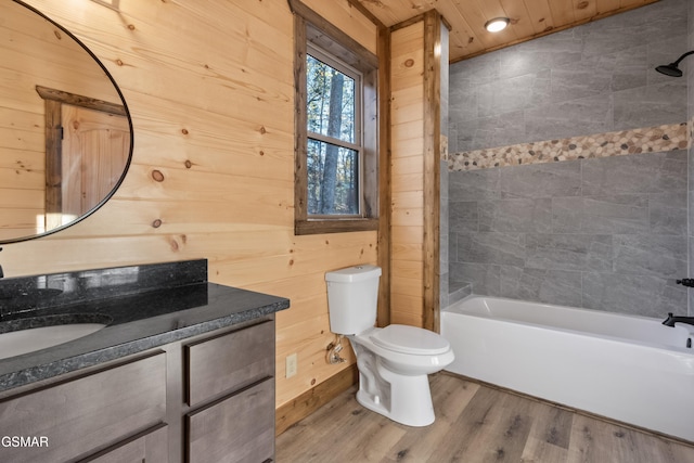 full bathroom with hardwood / wood-style flooring, wood walls, toilet, and tiled shower / bath