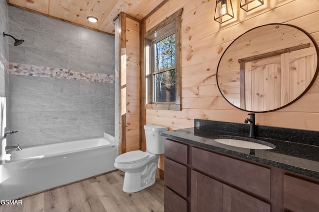 full bathroom featuring vanity, wood walls, shower / washtub combination, toilet, and wood-type flooring