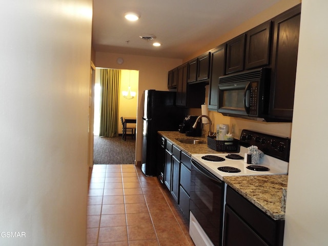 kitchen featuring dark brown cabinets, light tile patterned flooring, black appliances, visible vents, and a sink