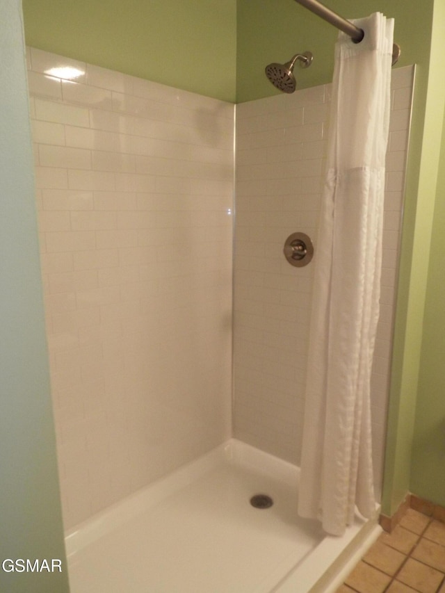 bathroom with a shower stall and tile patterned flooring