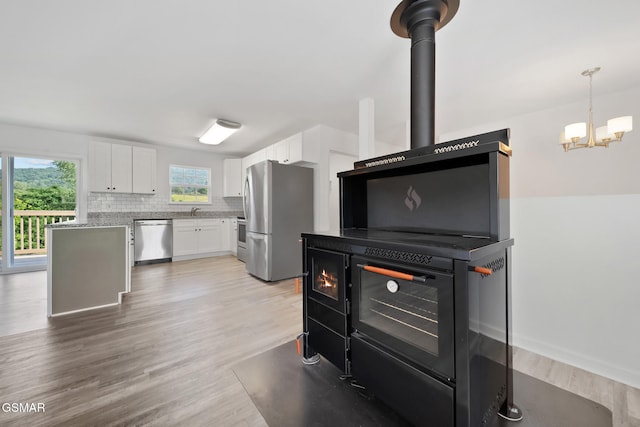 3206 Bativa Garden Ct, Sevierville, TN 37876 - kitchen featuring stainless steel appliances, white cabinetry, a chandelier, decorative backsplash, and light wood-type flooring