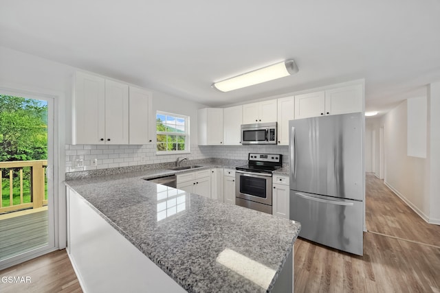 3206 Bativa Garden Ct, Sevierville, TN 37876 - kitchen with stainless steel appliances, decorative backsplash, light wood-style flooring, light stone counters, and white cabinetry