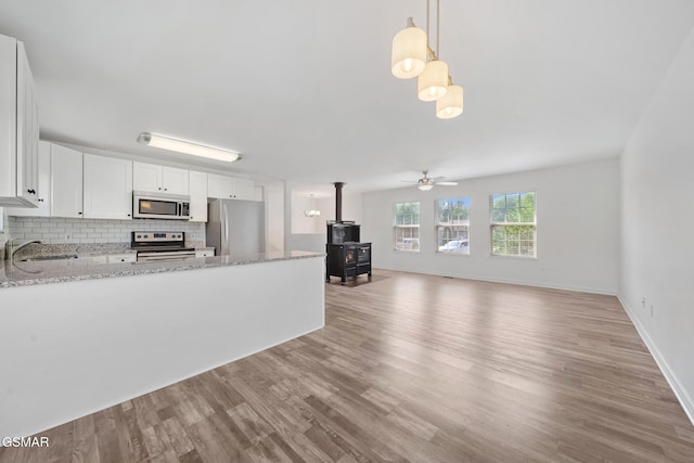 3206 Bativa Garden Ct, Sevierville, TN 37876 - kitchen with appliances with stainless steel finishes, a sink, a wood stove, light wood-style floors, and tasteful backsplash