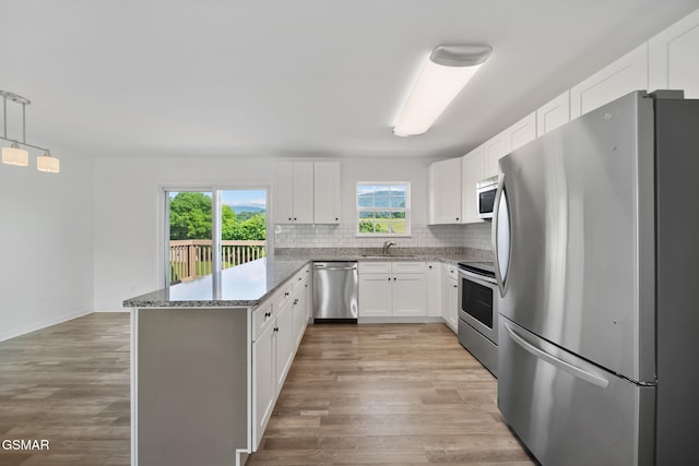 3206 Bativa Garden Ct, Sevierville, TN 37876 - kitchen with stainless steel appliances, a peninsula, tasteful backsplash, white cabinets, and light stone countertops