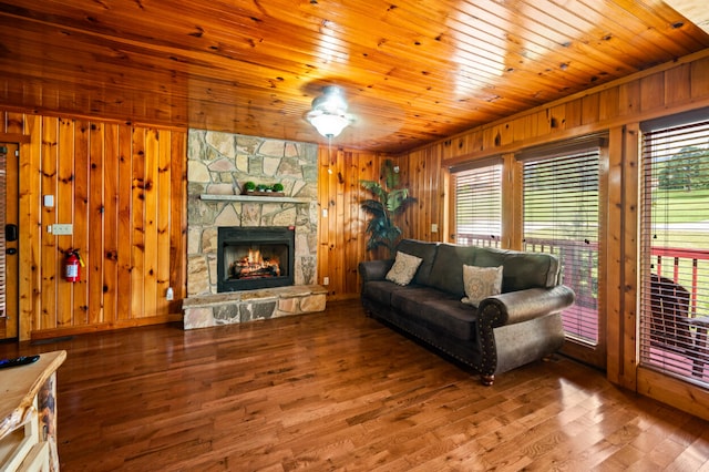 living room featuring ceiling fan, a stone fireplace, wood walls, wood ceiling, and hardwood / wood-style flooring