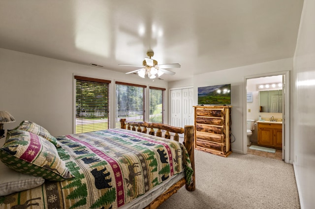 bedroom featuring ensuite bath, light colored carpet, ceiling fan, sink, and a closet