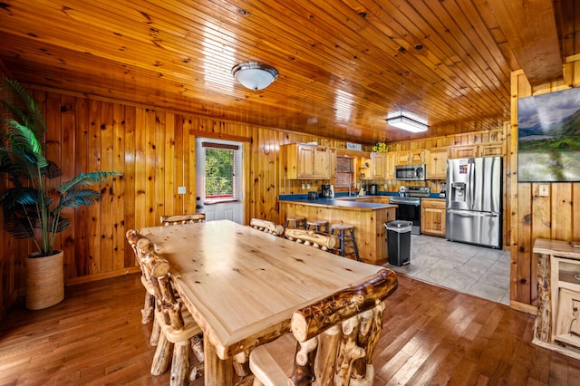 dining area featuring wood walls, light hardwood / wood-style floors, wood ceiling, and sink