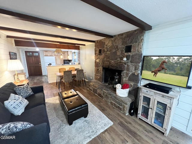 living room featuring beamed ceiling, wood-type flooring, and wooden walls