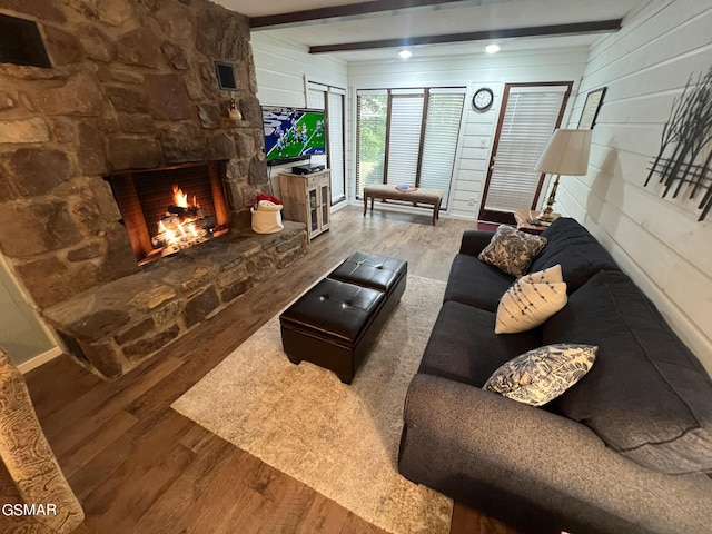 living room with hardwood / wood-style flooring, a fireplace, beam ceiling, and wooden walls