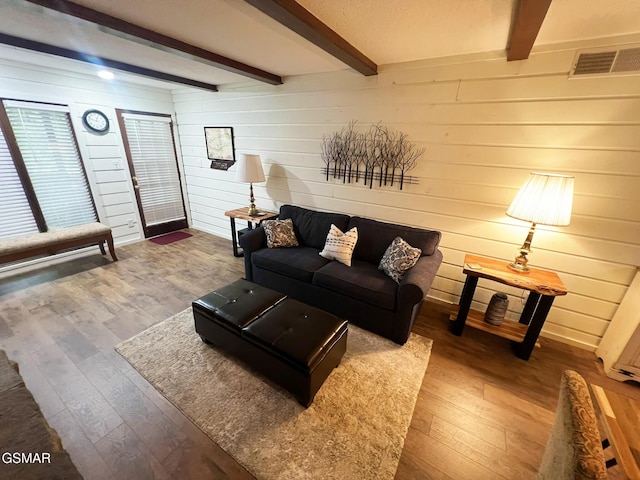 living room with beamed ceiling, hardwood / wood-style floors, and wooden walls