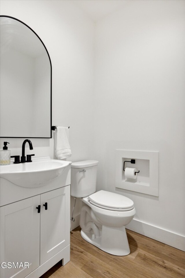 bathroom with hardwood / wood-style floors, vanity, and toilet