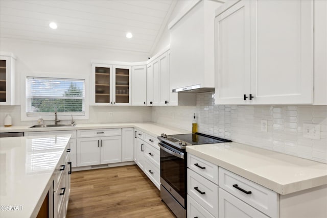 kitchen with sink, light hardwood / wood-style floors, lofted ceiling, stainless steel electric stove, and white cabinets