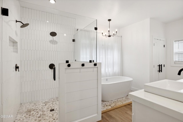 bathroom with hardwood / wood-style flooring, sink, plus walk in shower, and a chandelier