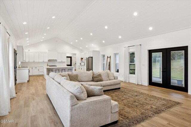 living room with french doors, high vaulted ceiling, light hardwood / wood-style flooring, and sink