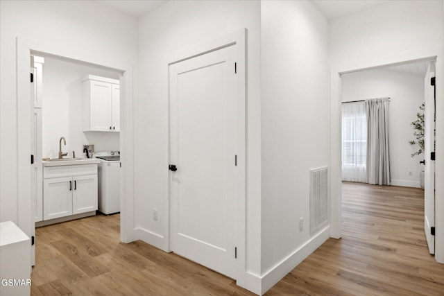 hallway with sink, light wood-type flooring, and washer / dryer