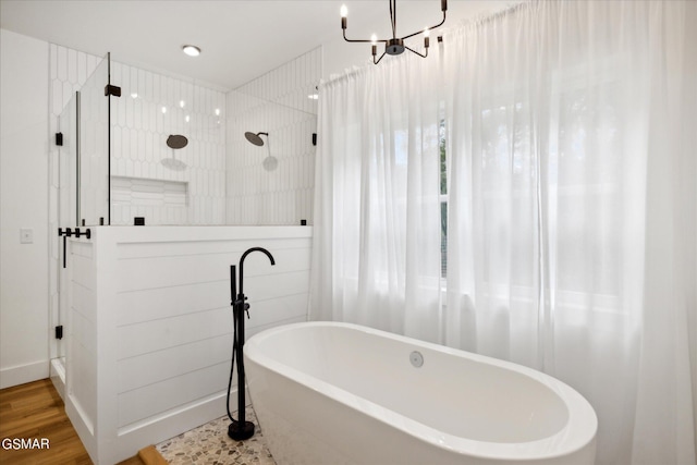 bathroom with shower with separate bathtub, hardwood / wood-style flooring, and an inviting chandelier